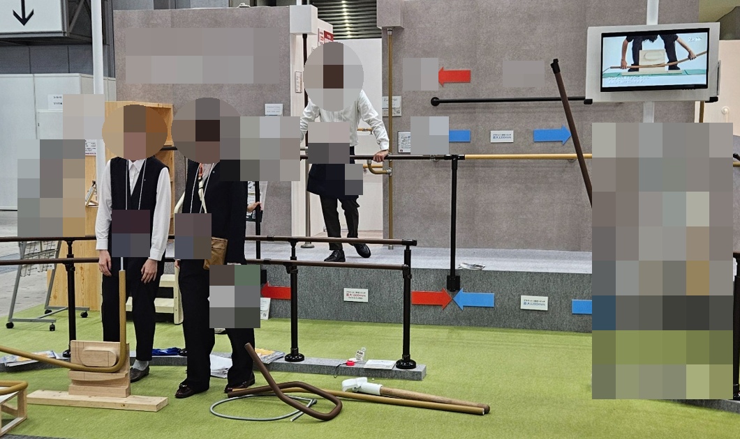 손잡이와 지지대가 전시된 부스 전경으로 관계자 얼굴과 명찰 및 기업 식별 정보를 가린 사진