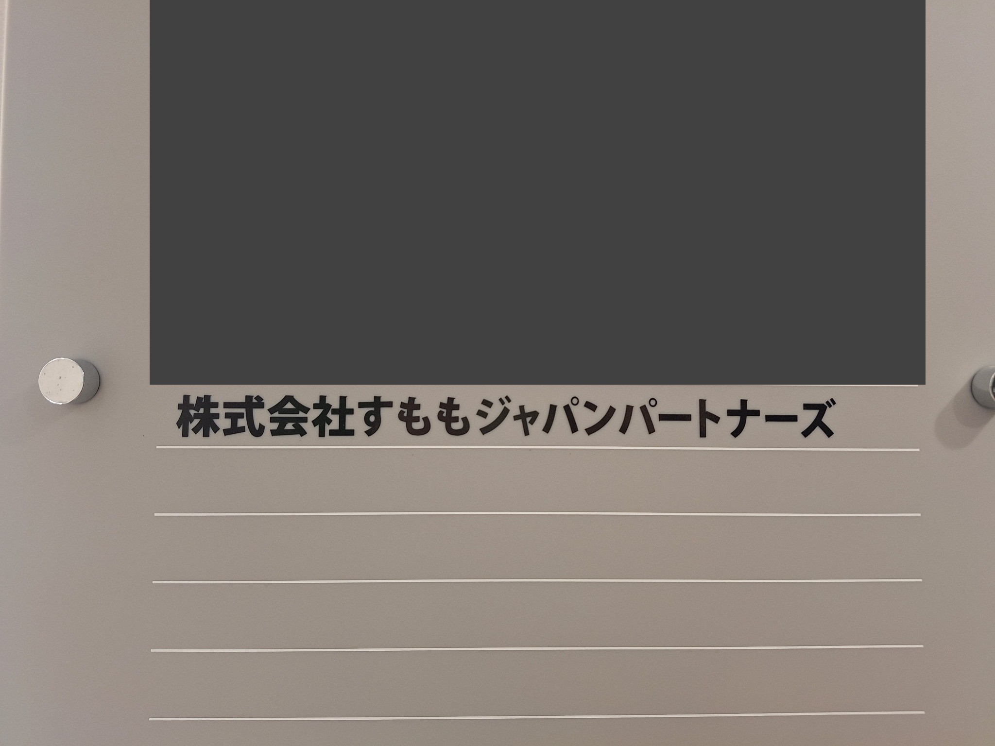 다른 입주사명을 가린 안내판 하단에 株式会社すももジャパンパートナーズ라는 법인명이 표시되어 있다.