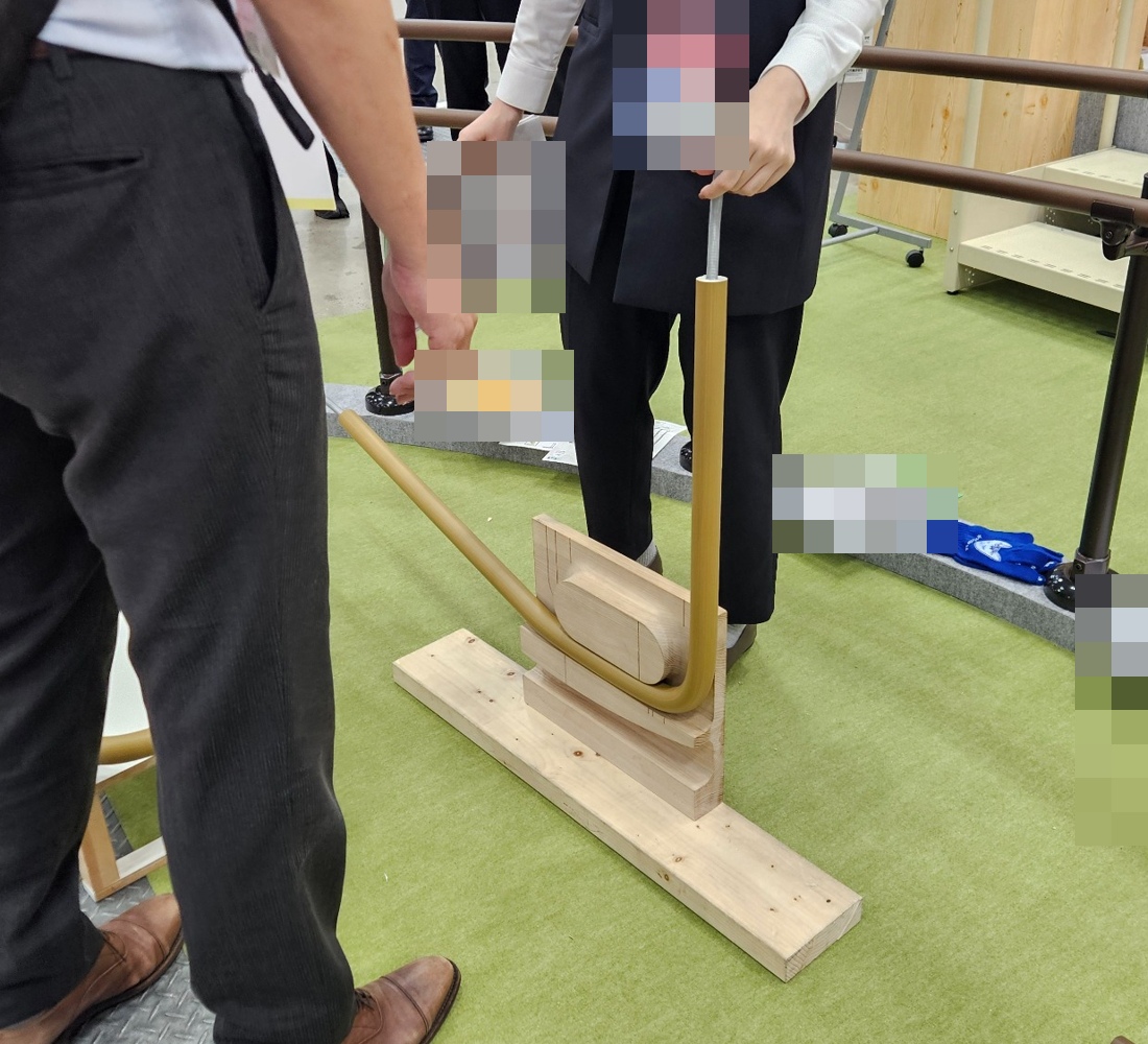 전시 관계자가 손잡이 형태의 제품을 설명하는 장면으로 얼굴이 나오지 않게 자르고 명찰과 자료를 가린 사진